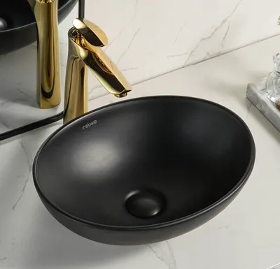 A black ceramic washbasin with a gold faucet on a marble countertop.