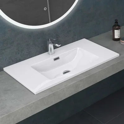 A modern bathroom sink with a chrome faucet on a white countertop.