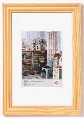 A framed picture of a room with a distressed cabinet and a chair.