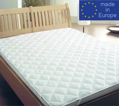 A white quilted mattress protector on a wooden bed frame.