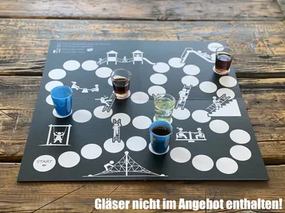 A board game with shot glasses filled with drinks placed on it, set on a wooden table.
