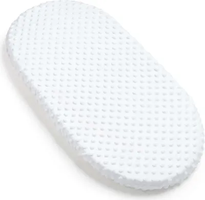 A white, oval-shaped baby mattress cover with a textured, dimpled surface, presented on a plain white background.