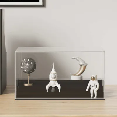 A clear acrylic display case containing space-themed figurines on a dark base, placed on a wooden surface.