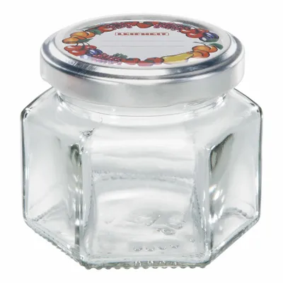 A hexagonal glass jar with a silver lid and a decorative label featuring fruits.
