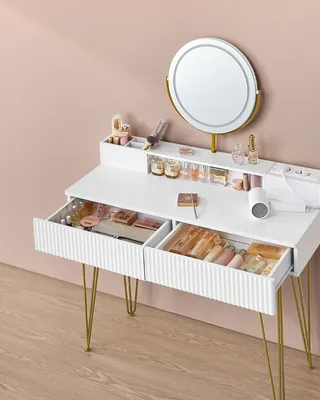 A white vanity table with gold legs, featuring a round illuminated mirror and organized drawers filled with makeup.