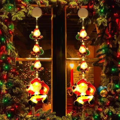 Christmas lights shaped like Santa Claus hanging in a window, decorated with Christmas trees and other festive lights.