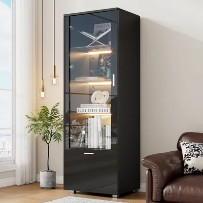 A modern living room with a black high-gloss display cabinet filled with books and decorative items, next to a brown leather armchair.