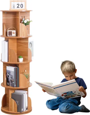 A boy reading a book next to a rotating bookshelf.