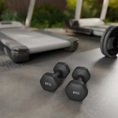 Two 6kg dumbbells are in the foreground on a concrete floor, with treadmills in the background.