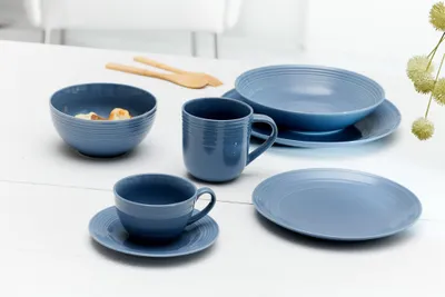 A set of blue ceramic dishes arranged on a white table.