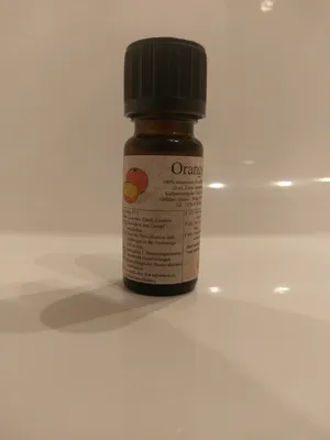 Kleine braune Flasche mit einem schwarzen Verschluss. Auf dem Etikett steht "Orange".