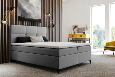 A bedroom scene with a large boxspring bed as the focal point, complemented by decorative elements and furniture.