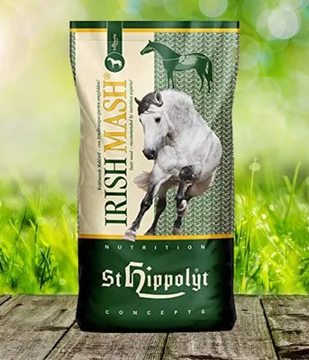 A bag of St. Hippolyt Irish Mash horse feed is shown in a natural outdoor setting with grass and sunlight.
