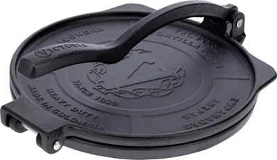 A black cast iron tortilla press is shown from a top-down diagonal angle.