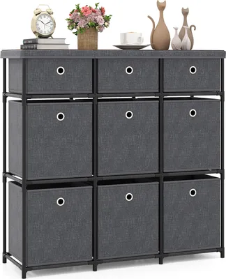 A gray fabric dresser with nine drawers is displayed against a white background. Decorative items, including a clock, flowers, and cat figurines, are placed on top of the dresser.
