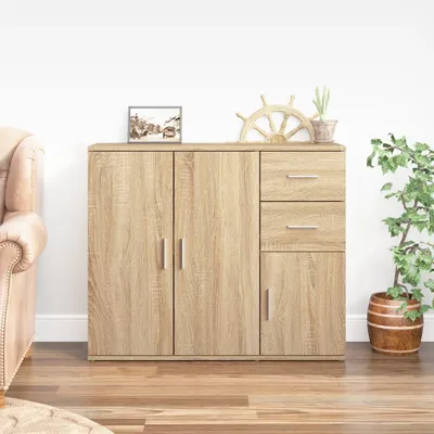 A wooden sideboard with drawers and doors, placed in a room with a sofa and a plant.