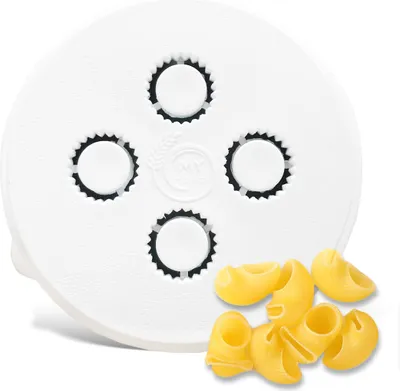 A white pasta maker attachment with several circular cutouts and a pile of elbow macaroni pasta next to it on a white background.