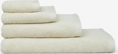 A stack of four cream-colored towels of varying sizes, neatly folded.
