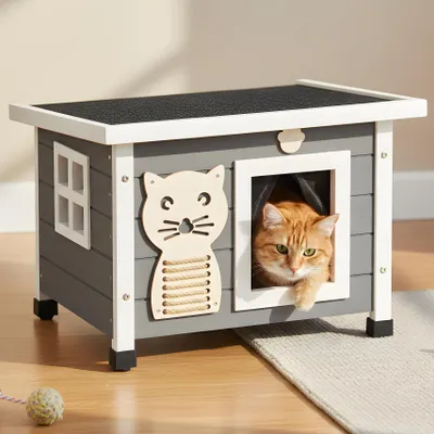 An orange cat is peeking out of a wooden cat house with a scratching post.