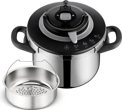 A silver and black pressure cooker with a steaming basket in front of it, set against a white background.