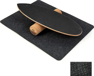 A balance board with a cork roller on a dark gray mat, set against a white background.