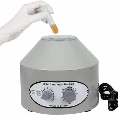 A gloved hand is holding a test tube over a laboratory centrifuge.