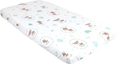 A white crib sheet with a pattern of deer and leaves.