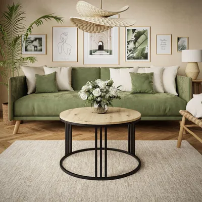 A living room scene featuring a green sofa, a round wooden coffee table, and wall art.