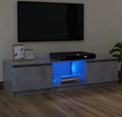 A modern TV stand with LED lighting in a concrete gray finish, featuring two cabinets and an open shelf with a Blu-ray player and books.