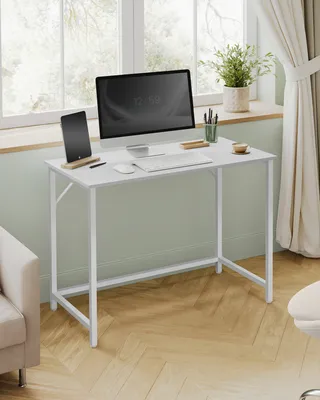 A white desk with a computer, tablet, and plant on it, placed near a window with curtains.