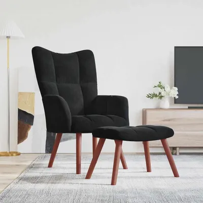 A black velvet armchair and ottoman are placed on a rug in a living room setting.