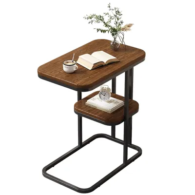 A small side table with a book, a cup of coffee, and a small alarm clock on it.