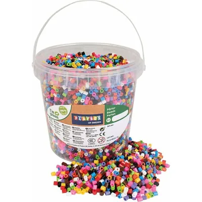 A bucket of colorful beads and a pile of beads spilled in front of it.
