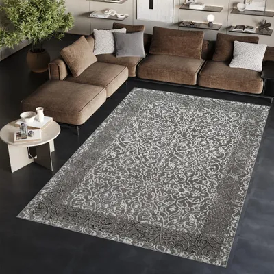 A living room scene with a large sectional sofa and a patterned rug.