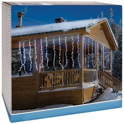 A wooden cabin with icicle lights draped over the porch during winter.