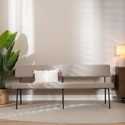 A bench in a room with a plant and a lamp.