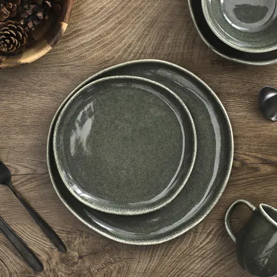 A top-down view of plates and cutlery on a wooden table, with pinecones in a bowl.