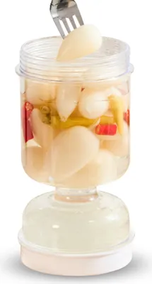 A clear, studio shot of a pickle jar with a fork lifting out a pickle.