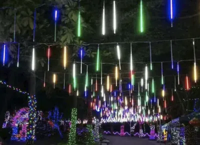 A pathway lined with trees decorated with colorful LED lights.