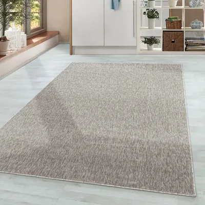 A rug is placed on a light-colored floor in a room with cabinets and a window.