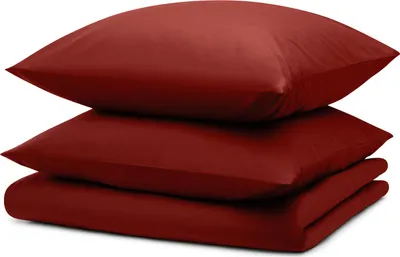 A stack of dark red bedding items, including two pillows and a folded duvet or comforter, is presented against a white background.