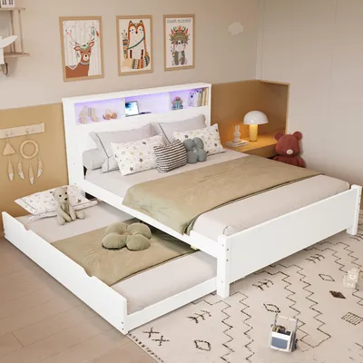 A white bed with a pull-out trundle bed in a bedroom setting, decorated with children's artwork and a teddy bear.