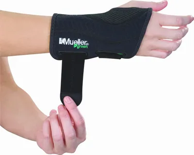A person's hand and wrist are shown wearing a black Mueller Greenline wrist brace.