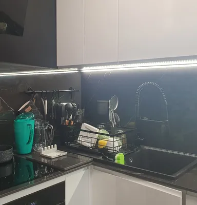 A modern kitchen sink area with a dish drying rack, faucet, and various kitchen utensils.