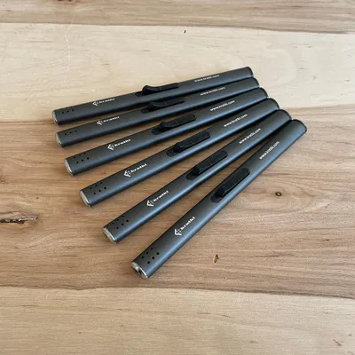 Several gray lighters are arranged on a wooden surface.