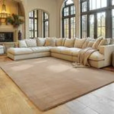 A spacious living room with a large sectional sofa and a beige rug.