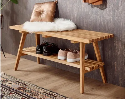 A wooden bench with two shelves, holding shoes and decorative items, placed on a rug in front of a textured wall.