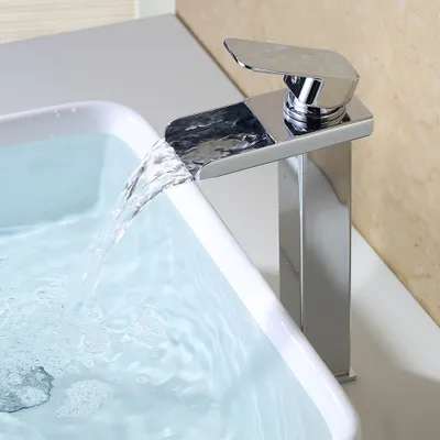 A close-up shot of a modern chrome waterfall faucet pouring water into a white sink.