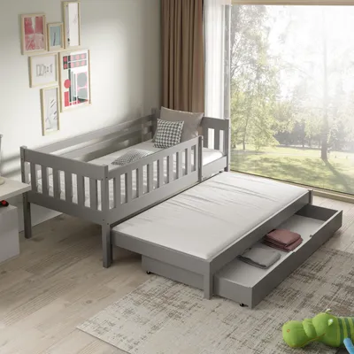A child's bed with a pull-out trundle bed in a room with a large window overlooking a garden.