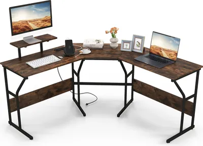 An L-shaped desk with a monitor, laptop, and decorative items.
